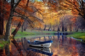 Осенний парк с лодкой на пруду