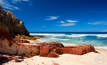 Песчаный берег с большими красными камнями